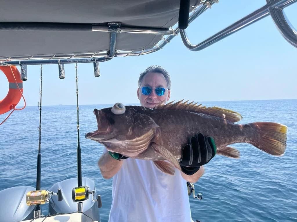 Guest with a fresh catch on a Horizon Blue private fishing charter from Al Mouj Marina